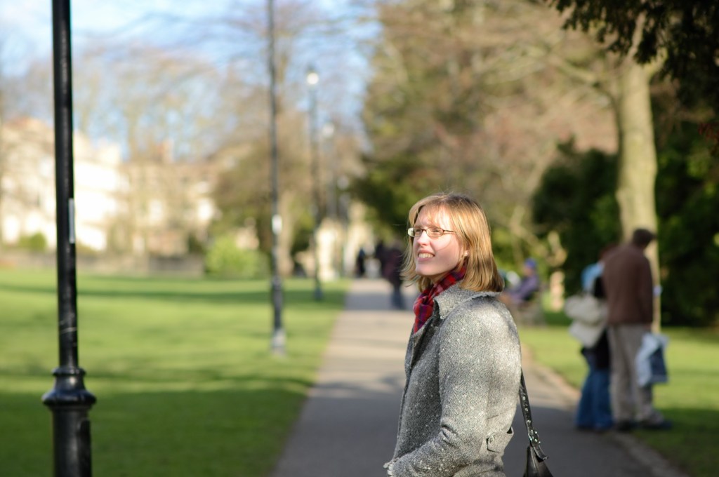 A photograph to introduce the author Clare. In the photo Clare is enjoying a calm moment among the trees whilst walking in a park on a bright winter's day.