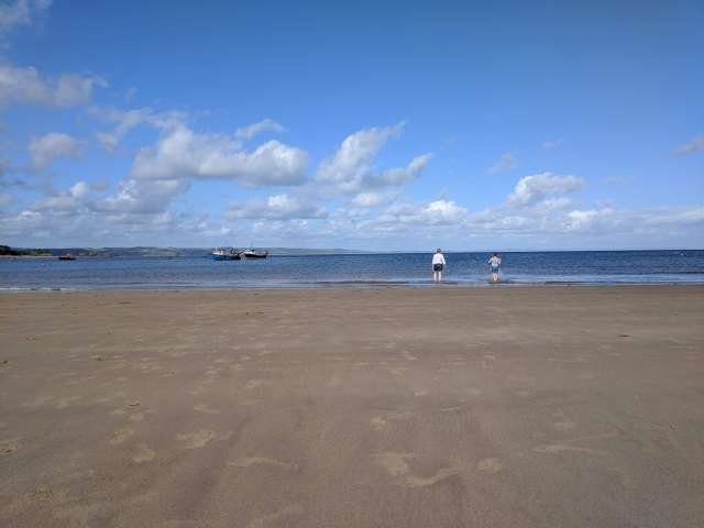 This photograph is included to allow the reader to understand the feeling of calmness that Clare is hoping to itntroduce into her lifestyle. The photo shows a mum and her son enjoying a quiet paddle in the sea together at the water's edge on a calm and tranquil sandy beach, amidst a summer blue sky and calm spacious blue sea. 