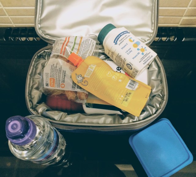 A lunch box unzipped to show it has been packed with drinks and food ready to take to school.