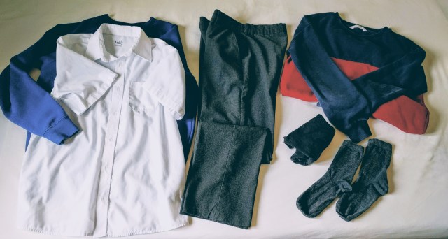 A set of clean school uniform (jumper, trousers, shirt, socks) set out ready for the day. The set also includes an extra spare jumper that can be worn during breakfast to protect the clean uniform from spills.